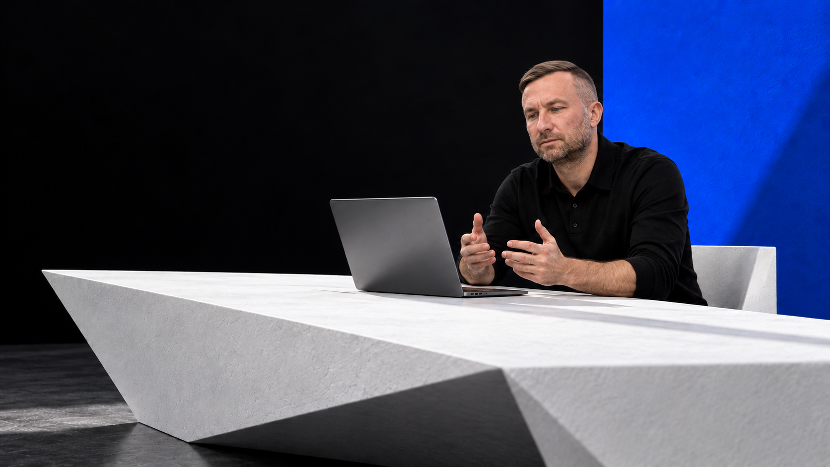 Brändivisuaal: Anti sülearvutiga valge laua taga musta ja sinise seina ees.